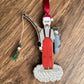 Decorative ornament of a fisherman with a red hat and apron on a wooden surface