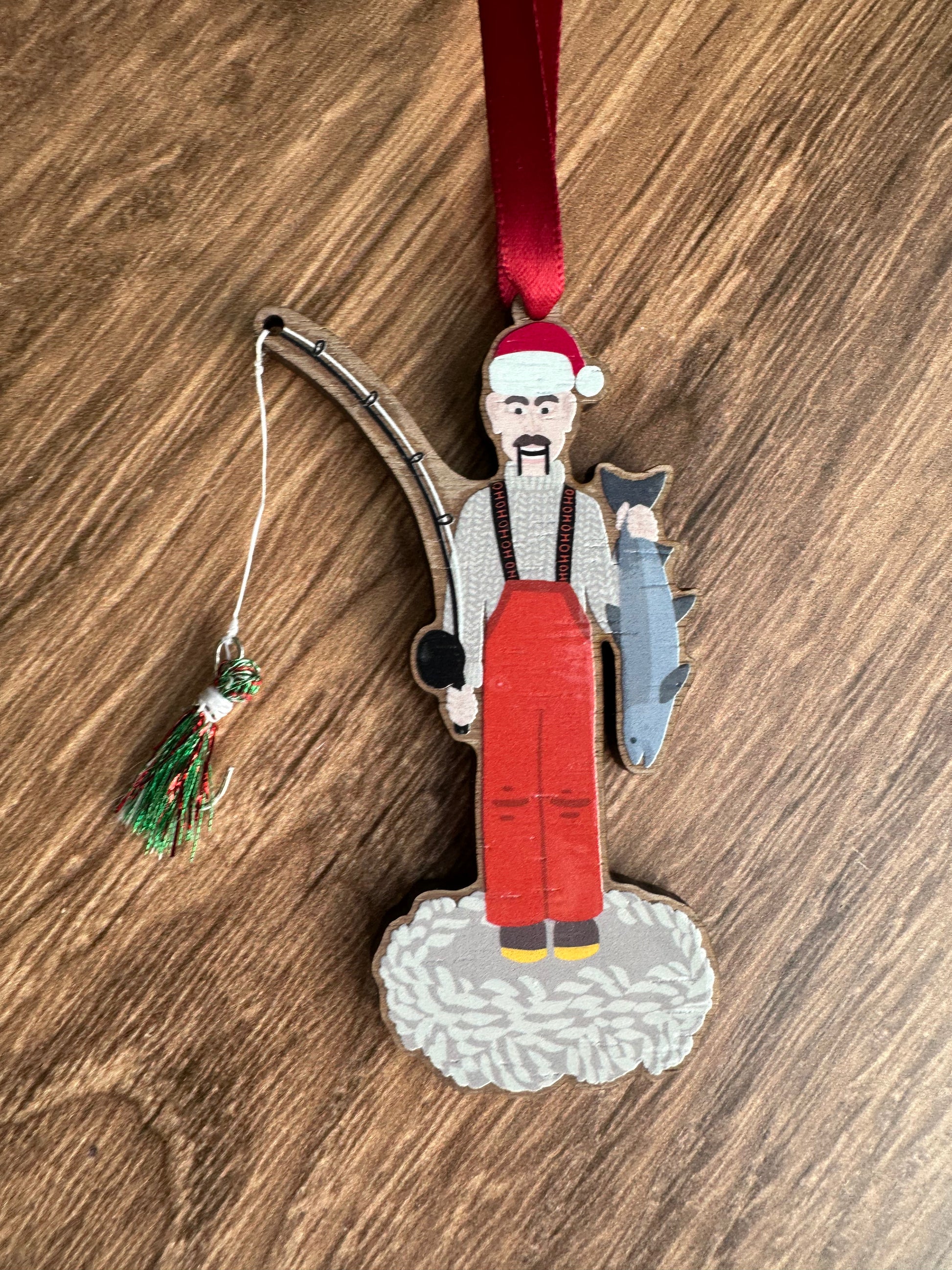 Decorative ornament of a fisherman with a red hat and apron on a wooden surface